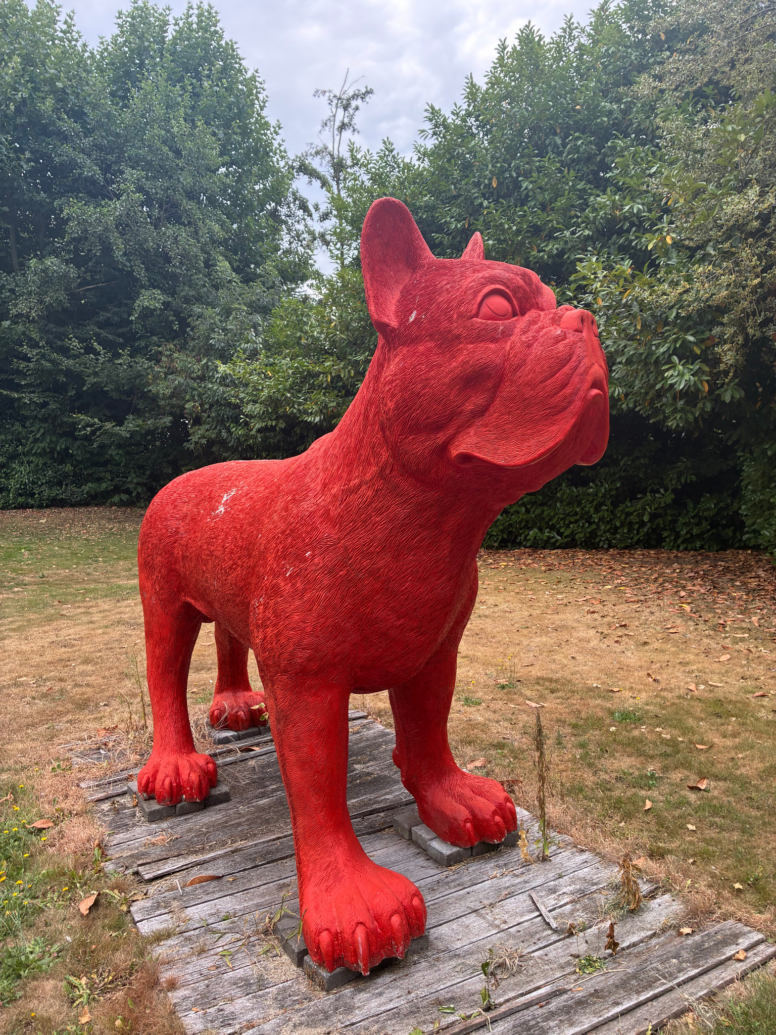 Groot rood decoratief hondenbeeld in een tuin