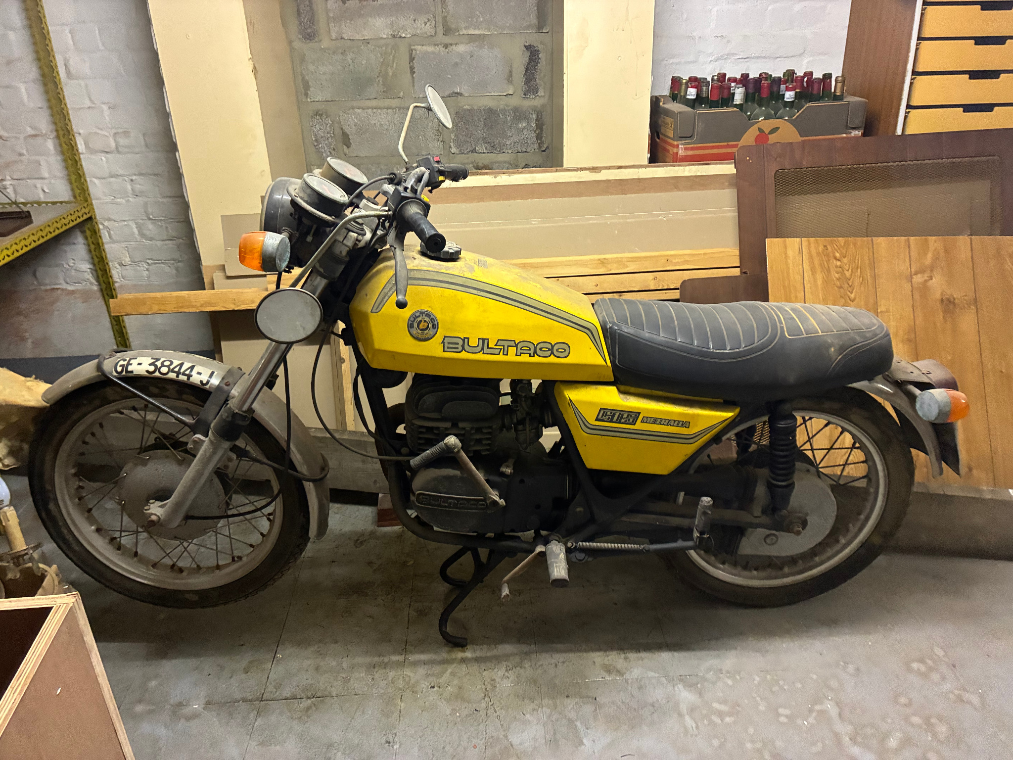 Gele klassieke Bultaco-motorfiets in een opslagruimte