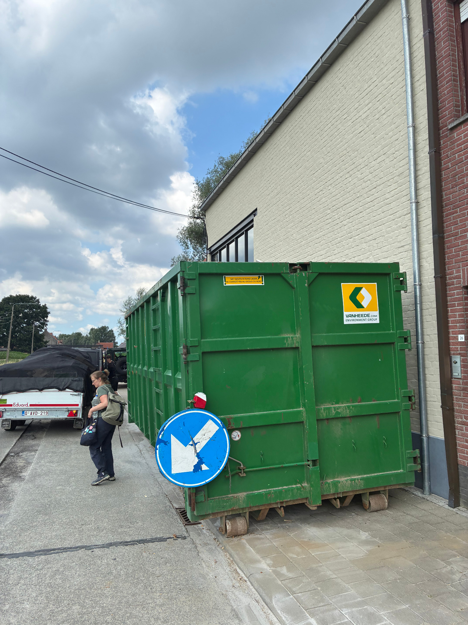 Grote groene afvalcontainer bij een woning tijdens een ontruiming