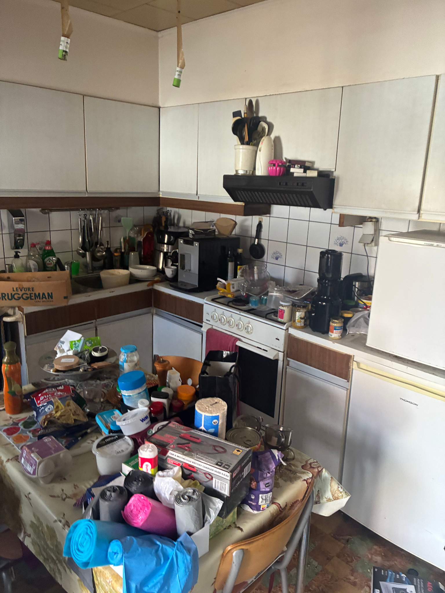 Keuken met huishoudelijke voorwerpen, apparaten en volle tafel
